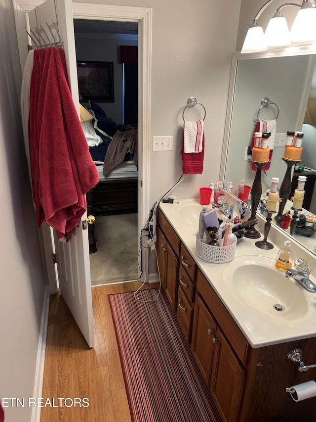 ensuite bathroom with ensuite bathroom, double vanity, wood finished floors, and a sink