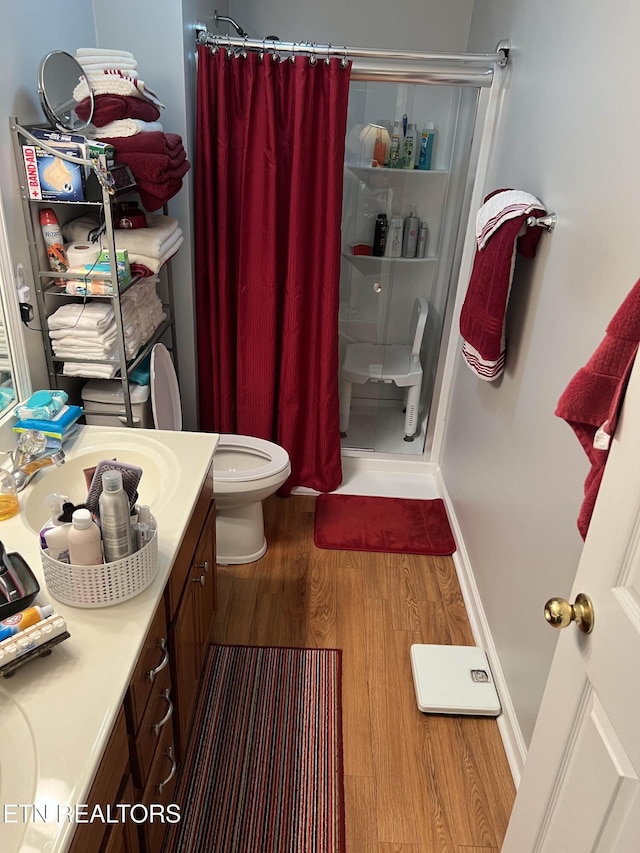 bathroom featuring toilet, wood finished floors, a shower stall, and vanity