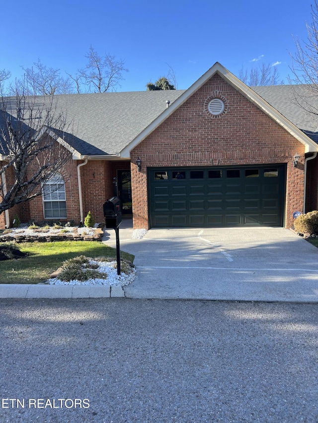 view of front of home featuring an attached garage, a shingled roof, concrete driveway, and brick siding