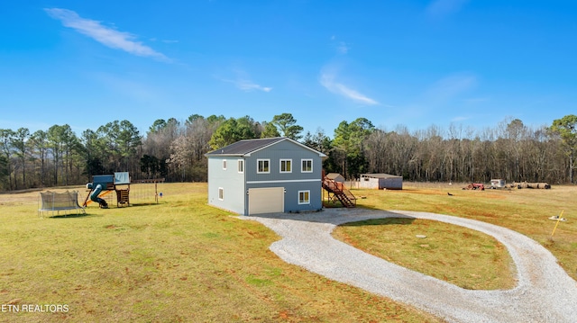 view of front of home with driveway, a garage, a trampoline, a playground, and a front yard