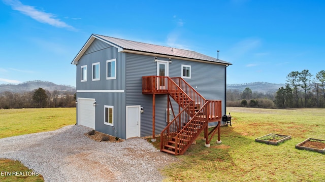 back of property featuring a mountain view, stairs, a lawn, a vegetable garden, and gravel driveway