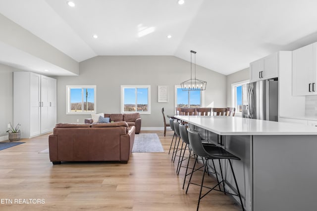 kitchen with plenty of natural light, white cabinetry, stainless steel refrigerator with ice dispenser, and a kitchen breakfast bar