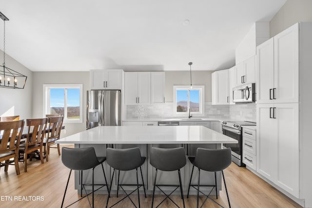 kitchen with stainless steel appliances, a breakfast bar, a sink, a center island, and decorative backsplash