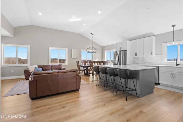 kitchen with stainless steel appliances, light wood-type flooring, white cabinets, and a breakfast bar area