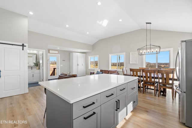 kitchen featuring light wood-type flooring, freestanding refrigerator, vaulted ceiling, and a barn door