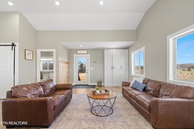 living room featuring lofted ceiling, a barn door, wood finished floors, and recessed lighting