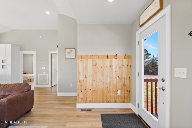 interior space featuring light wood-style floors, visible vents, vaulted ceiling, and baseboards