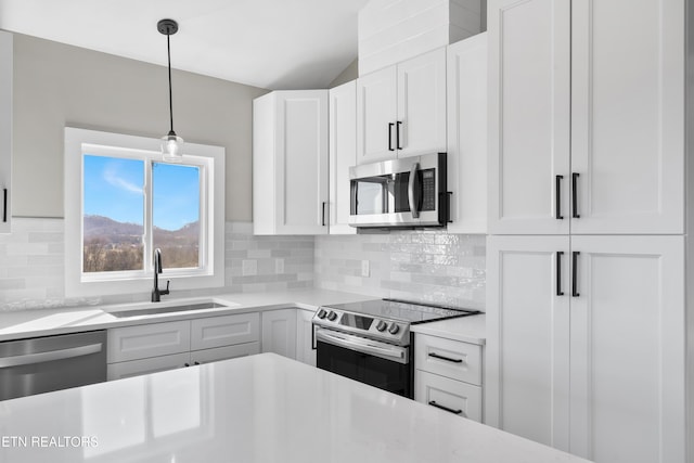 kitchen featuring decorative light fixtures, decorative backsplash, appliances with stainless steel finishes, white cabinetry, and a sink