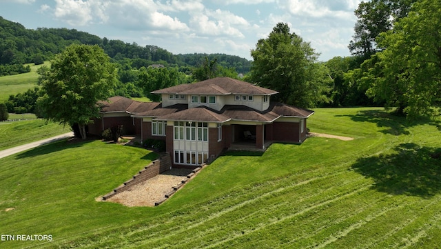 view of front of house featuring brick siding, a view of trees, and a front yard