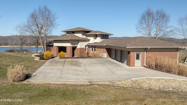 prairie-style home featuring a garage, brick siding, driveway, and a front lawn