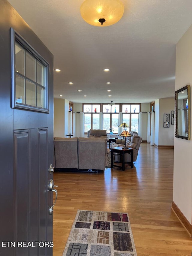 living room featuring recessed lighting, expansive windows, baseboards, and wood finished floors