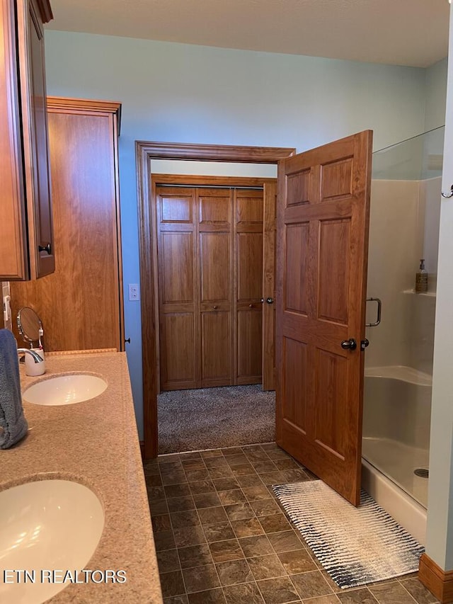 bathroom with double vanity, a sink, and a shower stall