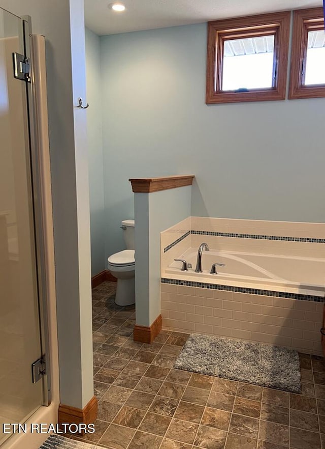 bathroom featuring toilet, a garden tub, a wealth of natural light, and a stall shower