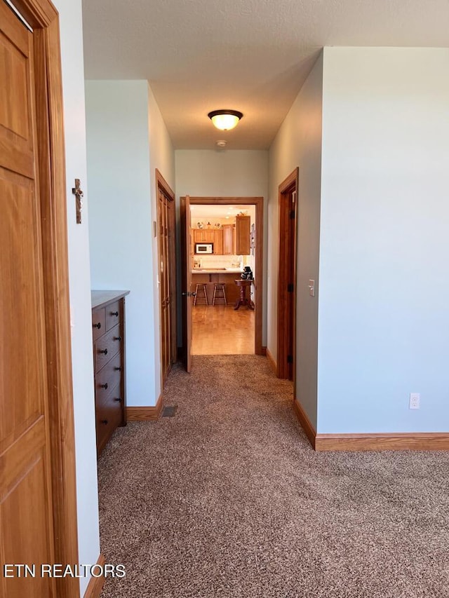 hallway with carpet floors and baseboards