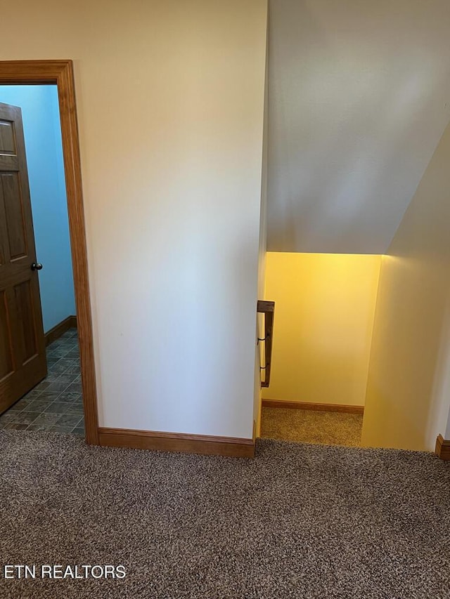 hallway featuring lofted ceiling, carpet, and baseboards