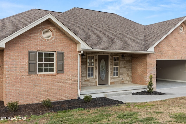 view of front facade with concrete driveway, a shingled roof, stone siding, and brick siding