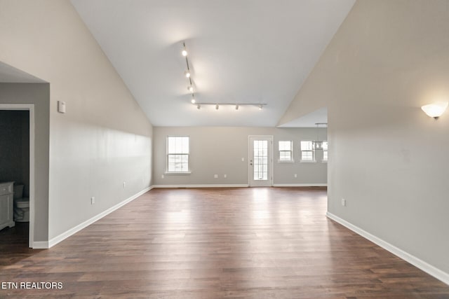 spare room with dark wood-style floors, high vaulted ceiling, track lighting, and baseboards