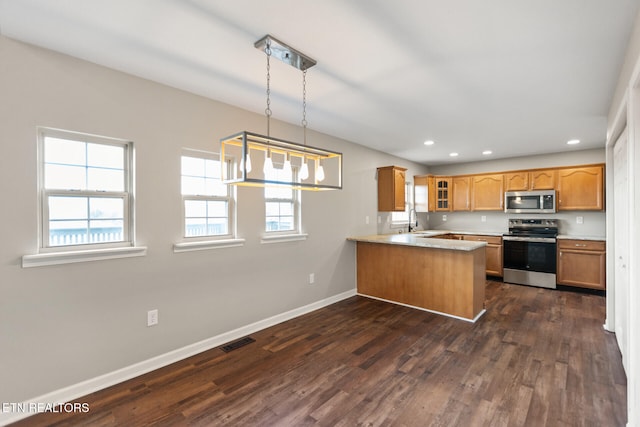 kitchen featuring baseboards, visible vents, a peninsula, stainless steel appliances, and a sink