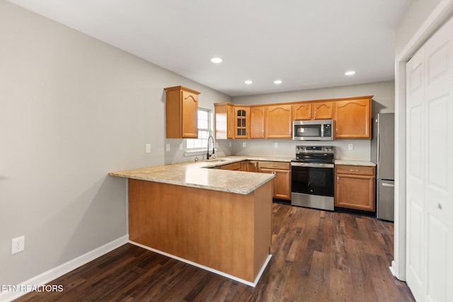 kitchen featuring baseboards, appliances with stainless steel finishes, glass insert cabinets, dark wood-style flooring, and a peninsula