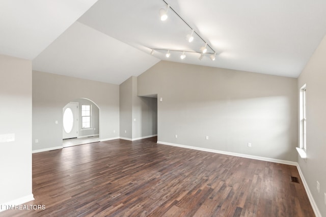 unfurnished room featuring arched walkways, dark wood-style flooring, lofted ceiling, visible vents, and baseboards