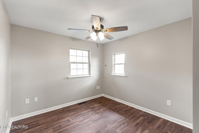 empty room featuring dark wood-style flooring, visible vents, ceiling fan, and baseboards