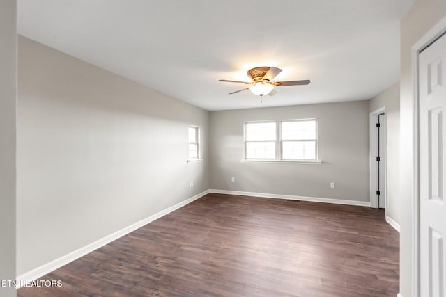 spare room featuring ceiling fan, dark wood-type flooring, and baseboards