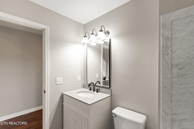 bathroom featuring vanity, wood finished floors, toilet, and baseboards