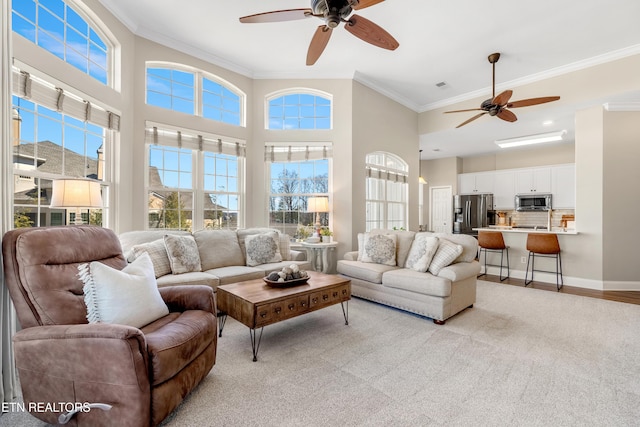 living area featuring baseboards, a high ceiling, light wood-type flooring, and crown molding