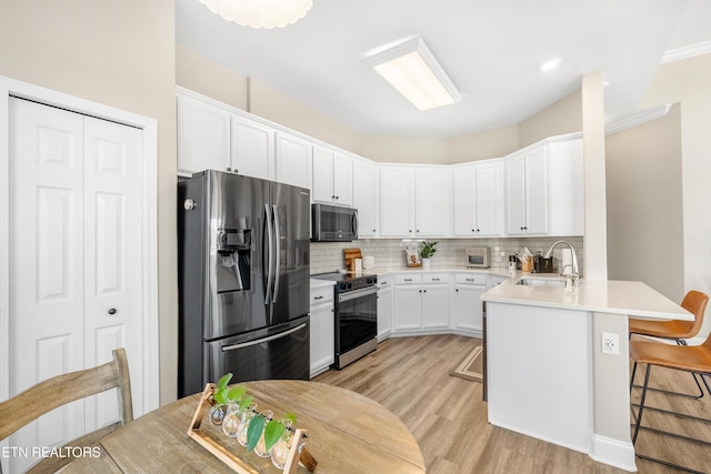 kitchen featuring appliances with stainless steel finishes, a sink, a peninsula, and tasteful backsplash