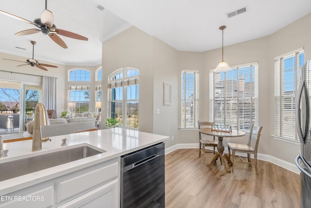 kitchen featuring visible vents, hanging light fixtures, a sink, light wood-type flooring, and dishwashing machine