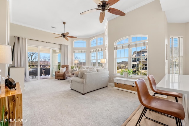 carpeted living room with ornamental molding, visible vents, plenty of natural light, and a towering ceiling