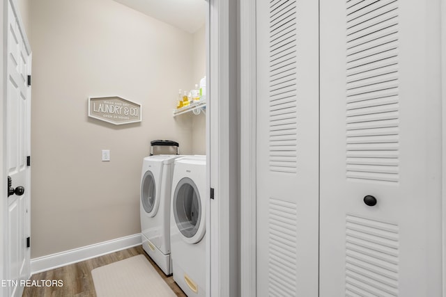 laundry room featuring laundry area, baseboards, washing machine and clothes dryer, and wood finished floors