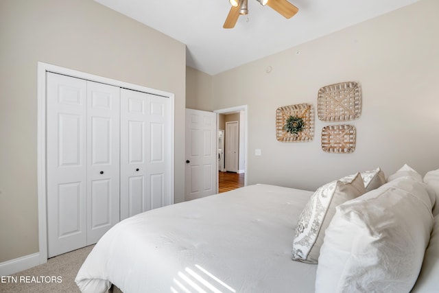 bedroom featuring lofted ceiling, ceiling fan, light colored carpet, baseboards, and a closet