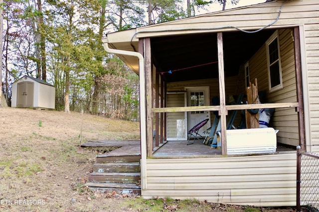 deck with an outdoor structure, fence, and a storage unit