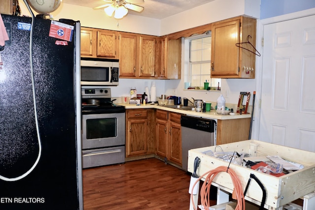 kitchen featuring brown cabinetry, dark wood-style floors, stainless steel appliances, and light countertops