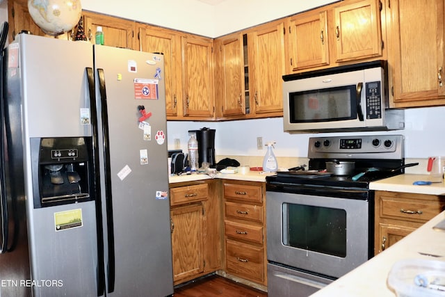 kitchen featuring stainless steel appliances, brown cabinetry, and light countertops