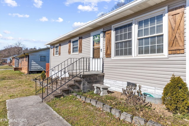 view of exterior entry featuring crawl space and a lawn