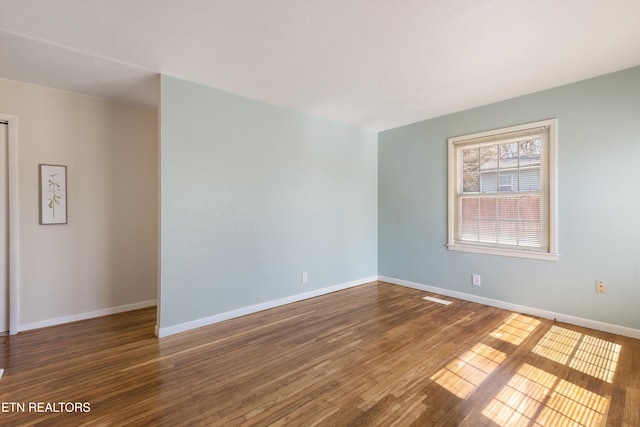 empty room with baseboards and wood finished floors