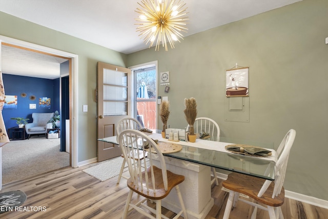 dining space with an inviting chandelier, baseboards, and light wood-style floors