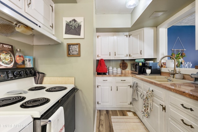 kitchen featuring electric stove, light countertops, light wood-type flooring, white cabinetry, and a sink