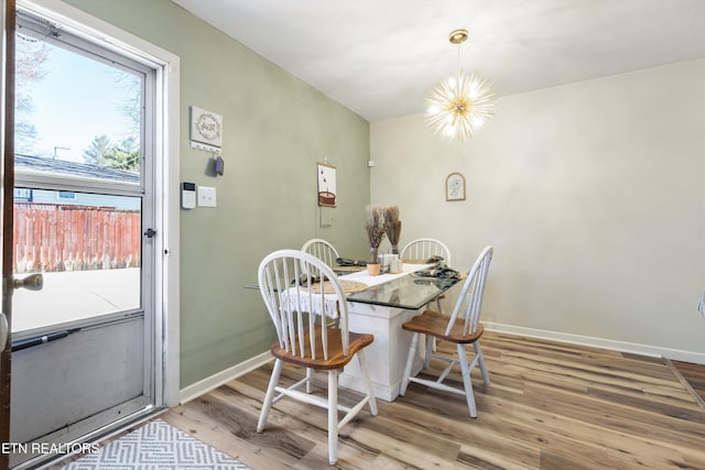 dining area featuring a chandelier, baseboards, and wood finished floors