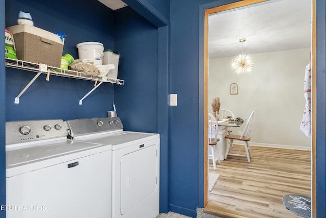 laundry room featuring a chandelier, washing machine and dryer, laundry area, baseboards, and light wood finished floors