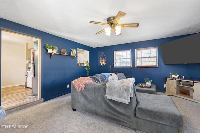 living room with ceiling fan, baseboards, and carpet flooring