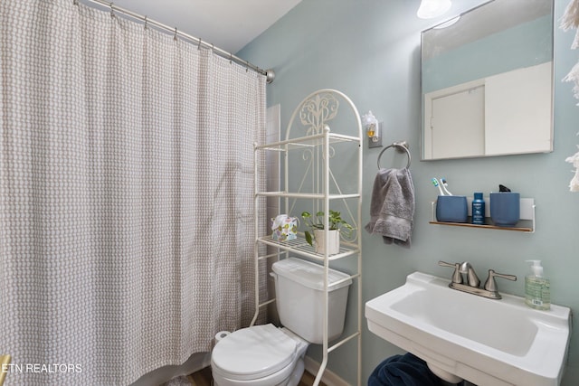 full bath with toilet, curtained shower, and a sink