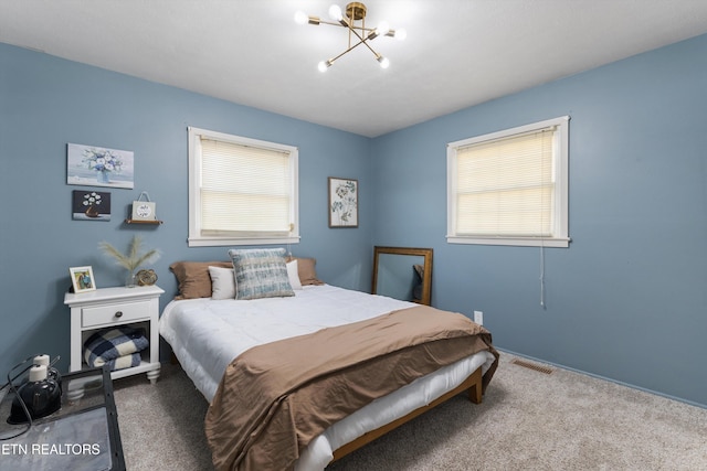 bedroom featuring carpet floors, multiple windows, visible vents, and an inviting chandelier