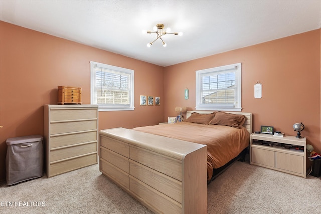 bedroom featuring a notable chandelier, multiple windows, and light colored carpet