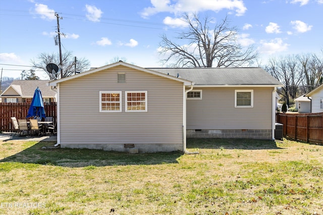 rear view of property with crawl space, fence, central AC unit, and a lawn