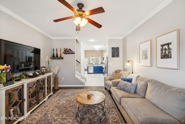 living area featuring stairs, baseboards, a ceiling fan, and crown molding