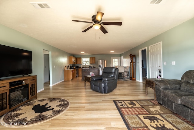 living area with light wood-type flooring, baseboards, visible vents, and a ceiling fan