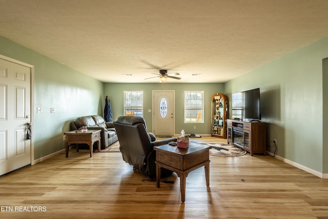 living room with baseboards, a glass covered fireplace, and light wood-style floors